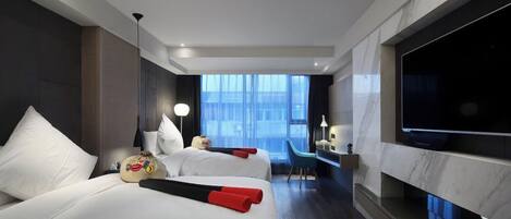 A modern hotel room with two beds, a TV, a desk, and a large window.