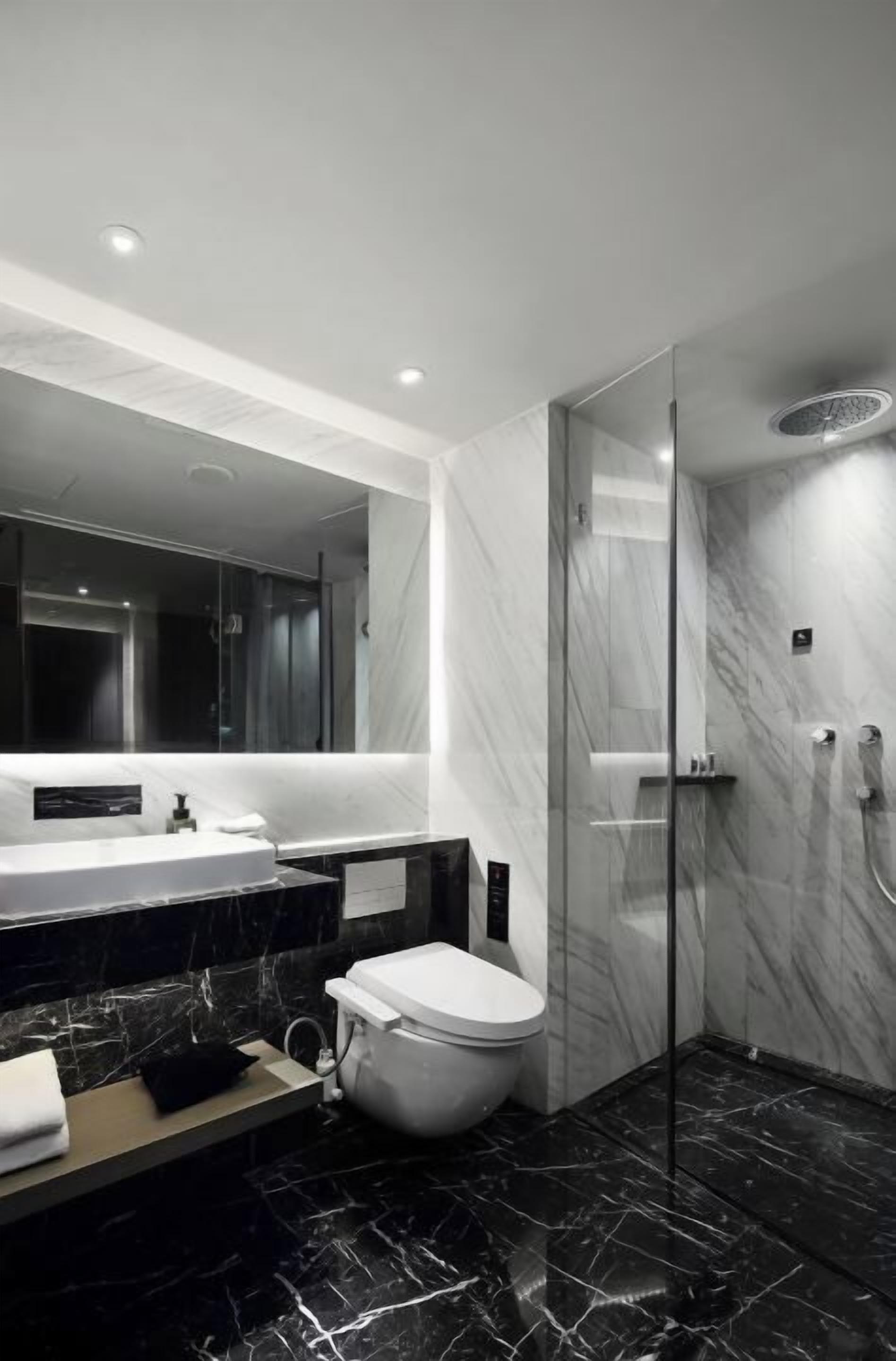 A modern bathroom with a large mirror, a bathtub, a toilet, and a glass-enclosed shower.
