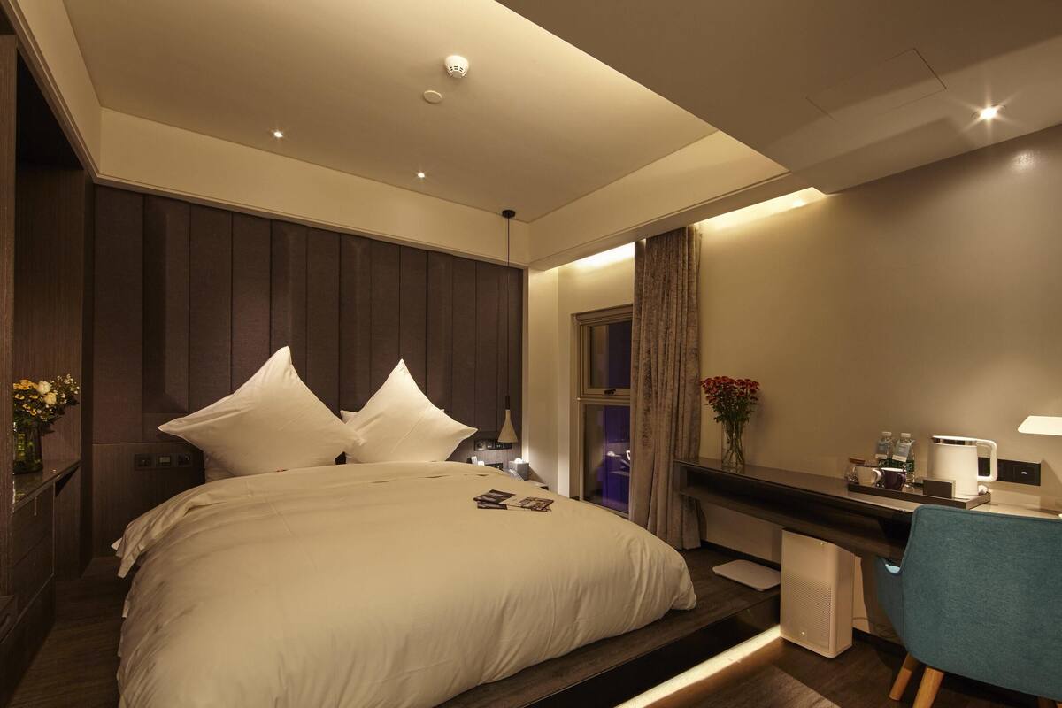 Ein modernes Hotelzimmer mit einem großen Bett, einem Schreibtisch und einem Stuhl.