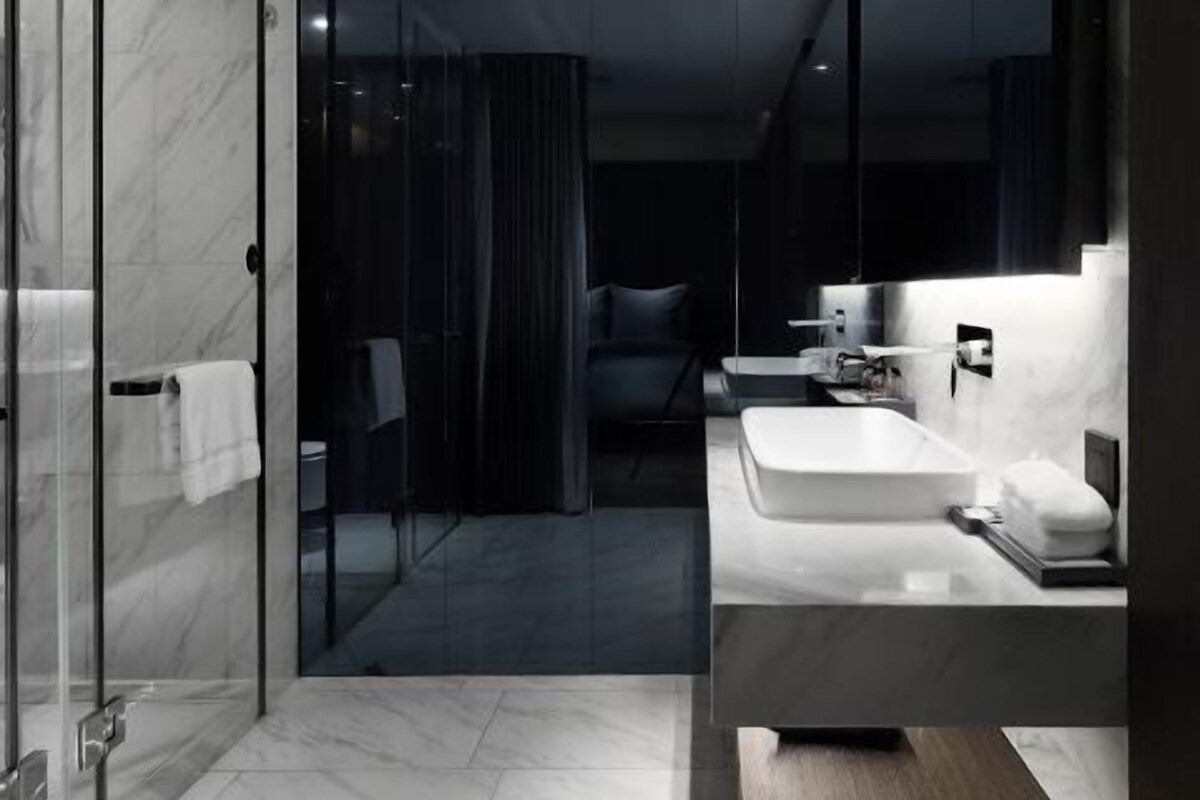 A modern bathroom with a glass shower enclosure, a large mirror, and a vanity with a sink and countertop.