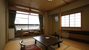 Una habitación japonesa tradicional con suelo de tatami, una mesa baja y un fusuma que da a un balcón.