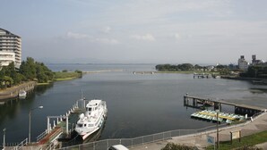 Un paseo ribereño con un muelle, un barco blanco grande y un edificio de varios pisos.