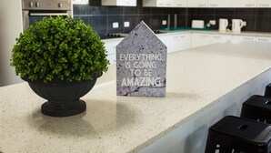 A kitchen counter with a potted plant and a house-shaped sign with text. - Aspire Mayfield (Mayfield)