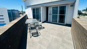 A modern building with a patio area featuring a table and chairs, large sliding glass doors, and a satellite dish on the roof. - Aspire Mayfield (Mayfield)