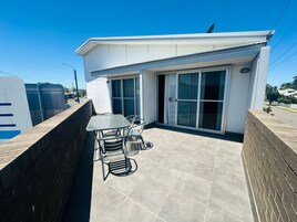 Un edificio moderno con un patio que tiene una mesa y sillas, grandes puertas correderas de vidrio y una antena parabólica en el techo.