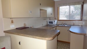 A compact kitchen with a microwave, sink, and a small countertop. - Goomeri Motel (Goomeri)