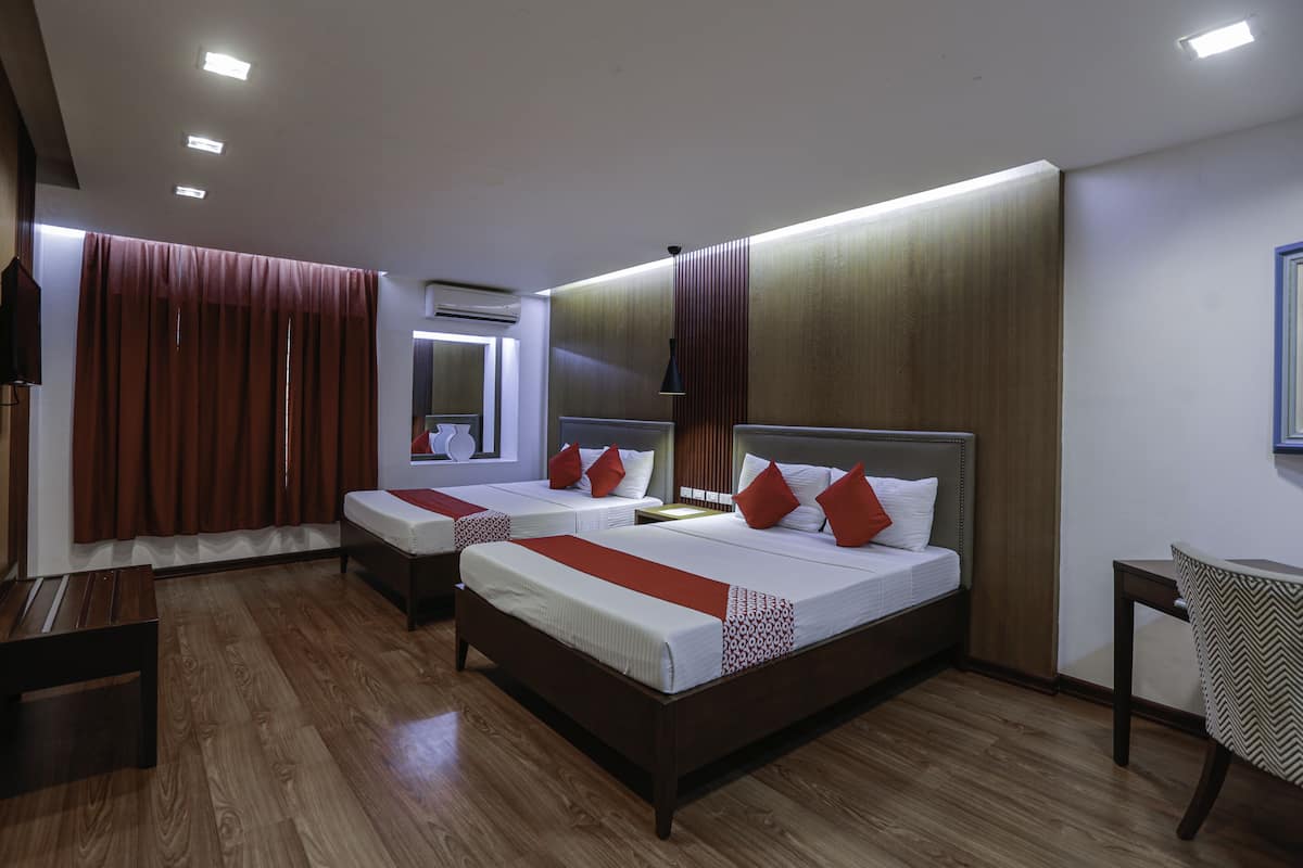 Een hotelkamer met twee bedden, houten vloeren en een grote spiegel.
