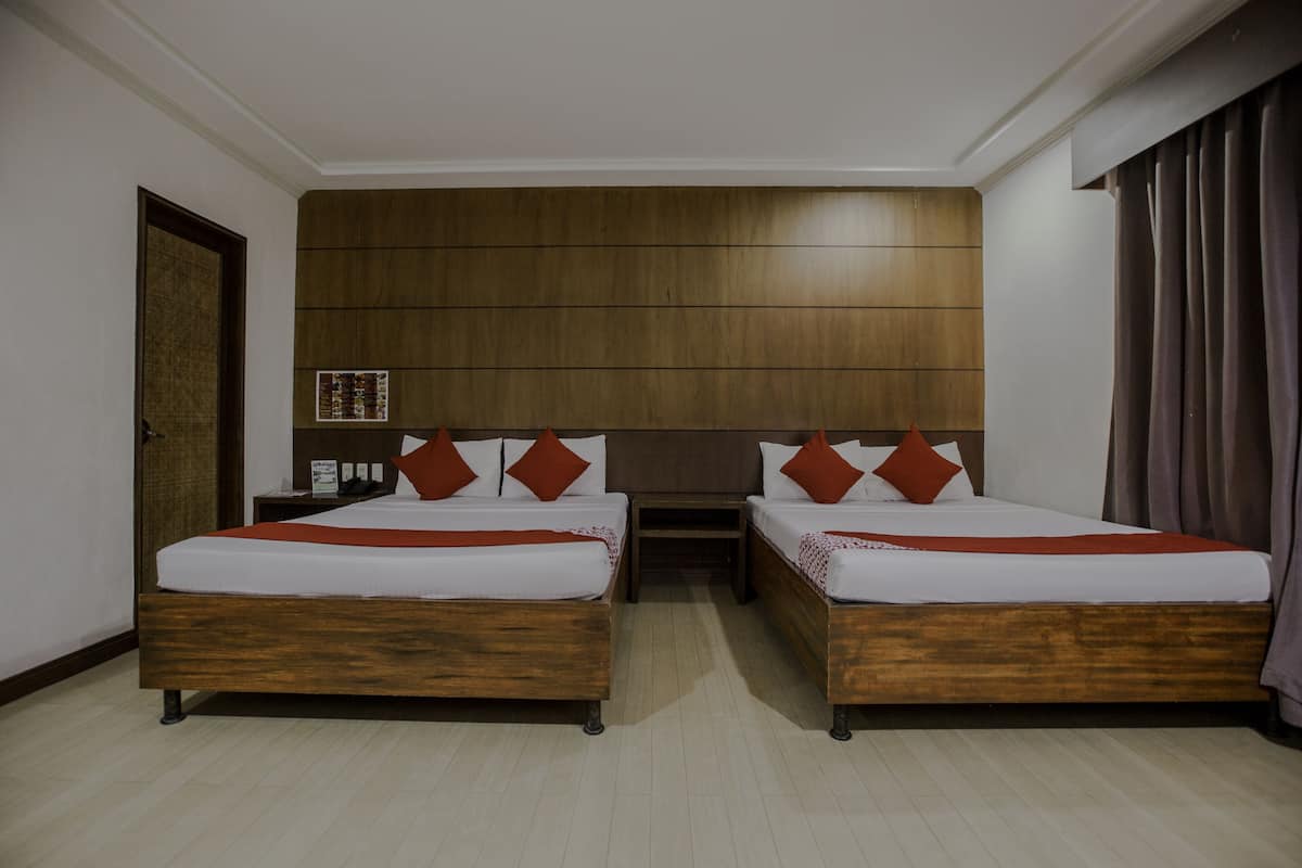 Een hotelkamer met twee houten bedden, wit beddengoed en rode kussens.