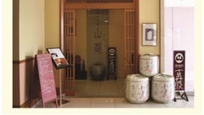 A traditional Japanese entrance with a wooden gate, a signboard, and large ceramic containers.