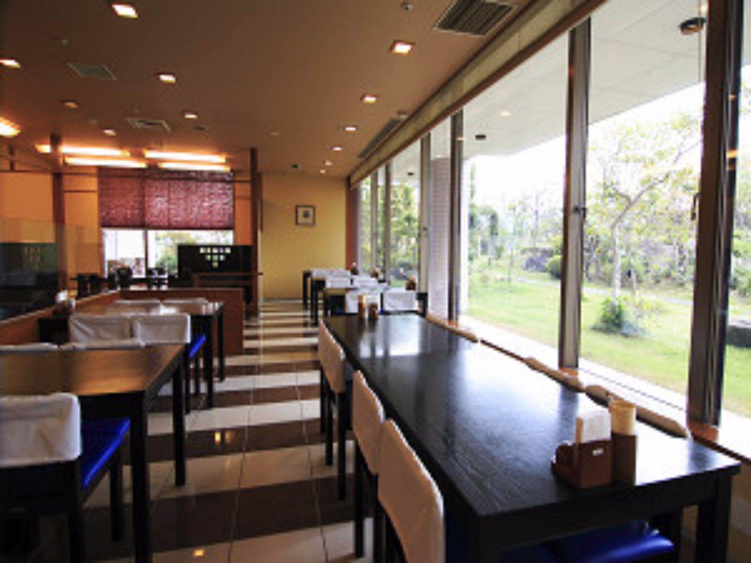 A restaurant with a long counter, chairs, and a view of the outdoors.