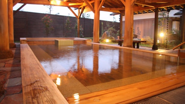 A wooden deck with a hot tub and stone flooring.