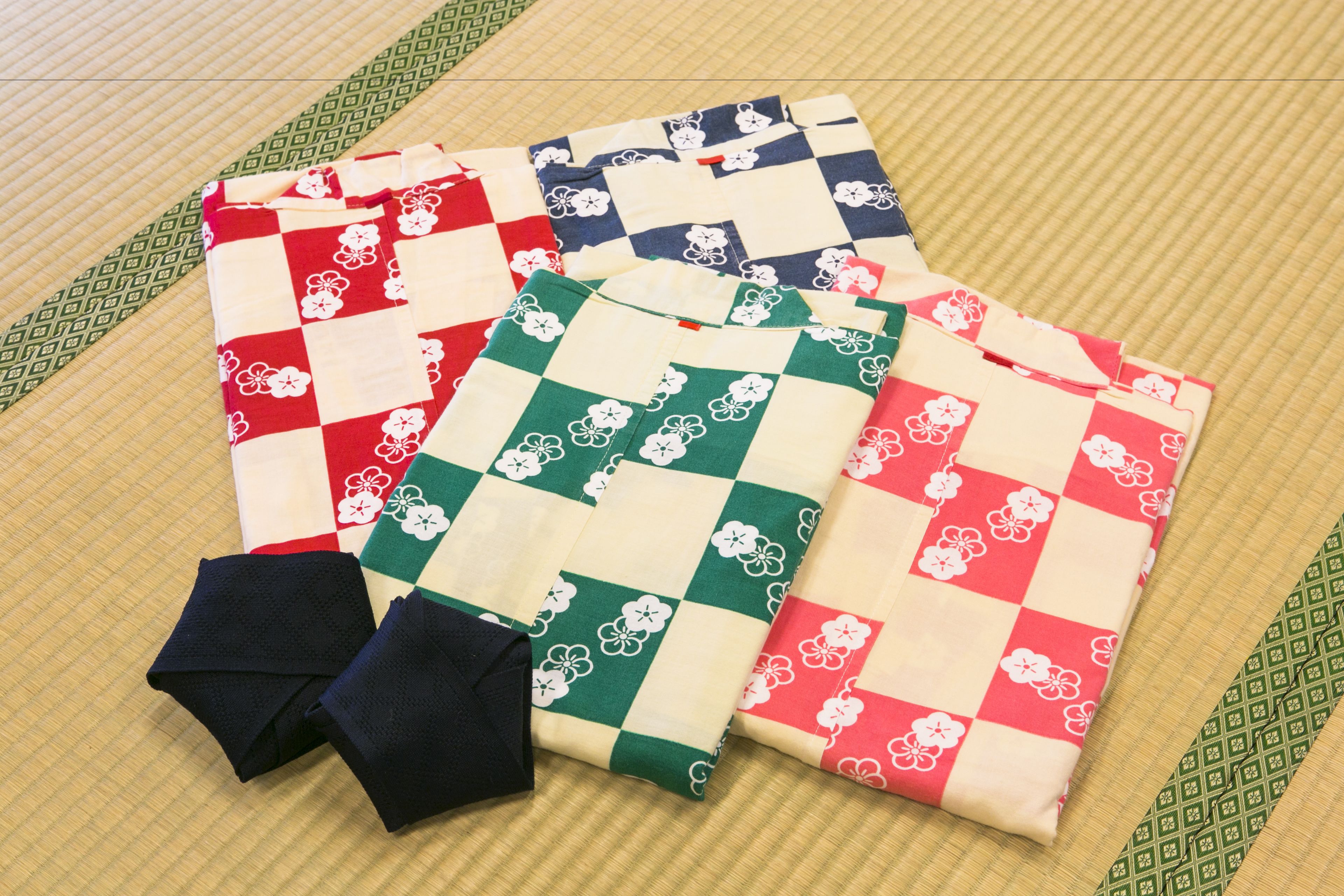 A set of traditional Japanese textiles with floral patterns, folded neatly on a tatami mat.