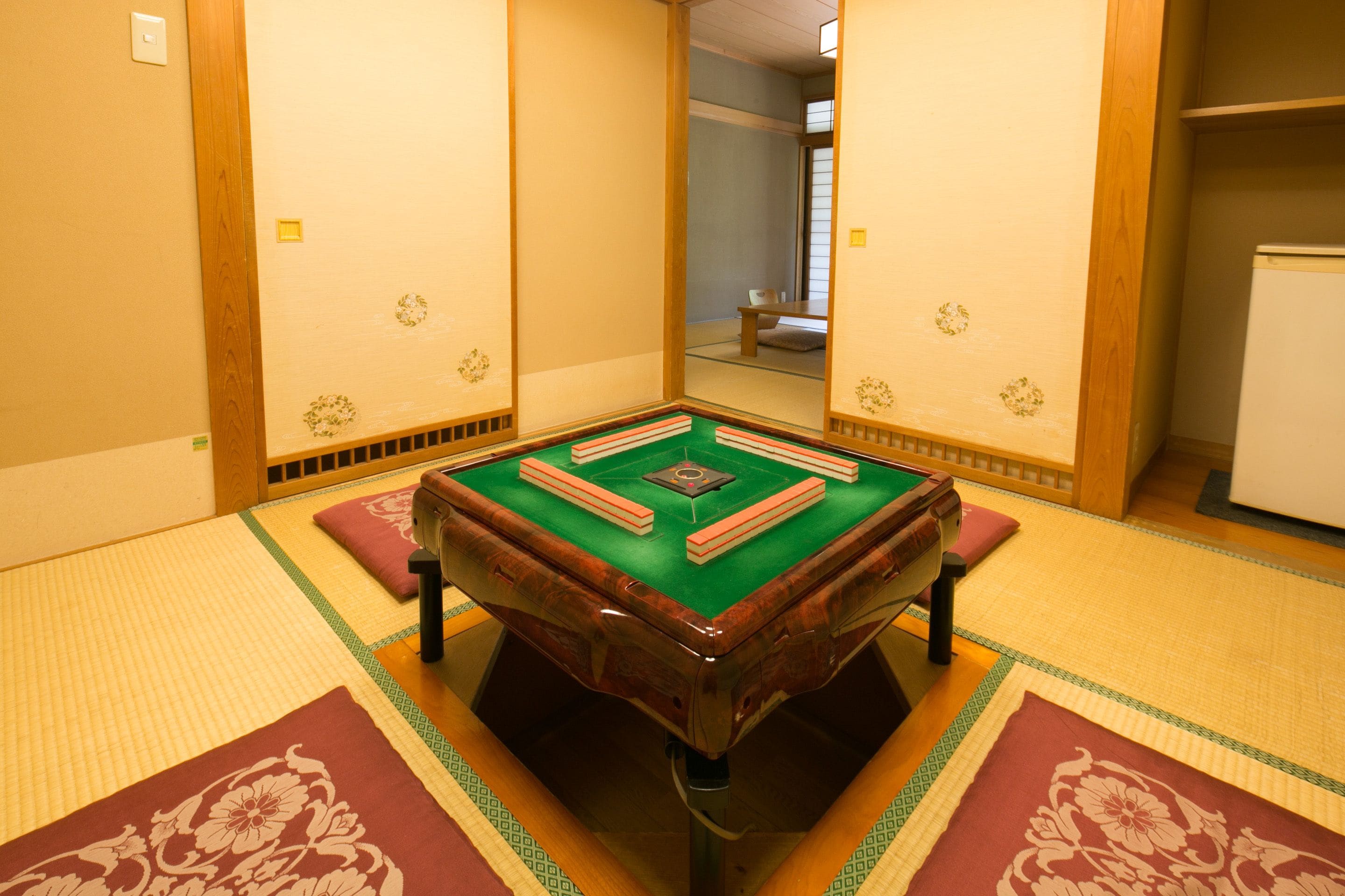 A tatami mat room with a green tatami mat table, wooden sliding doors, and a traditional Japanese aesthetic.