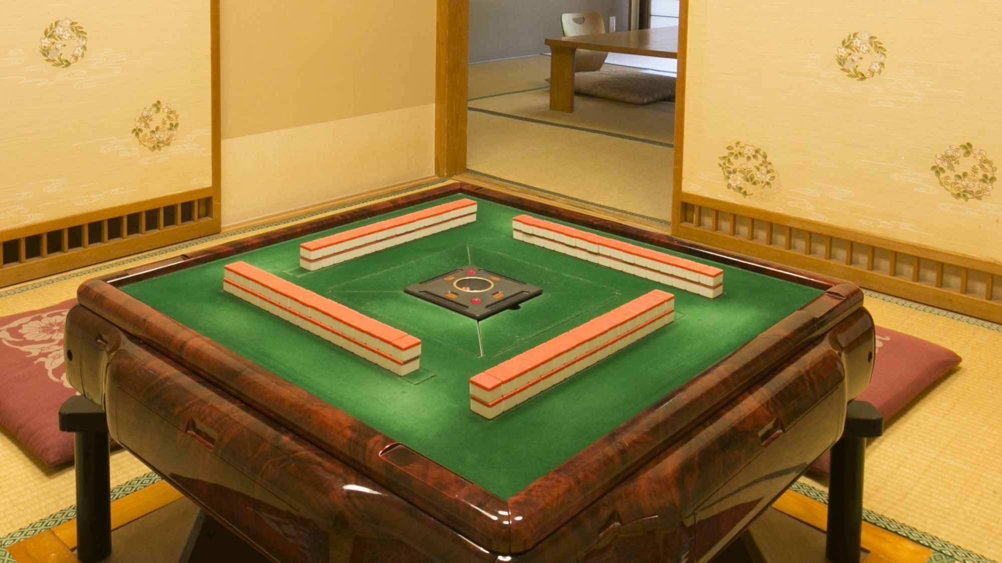 A tatami mat room with a shoji screen, a tatami mat table, and a wooden cabinet.
