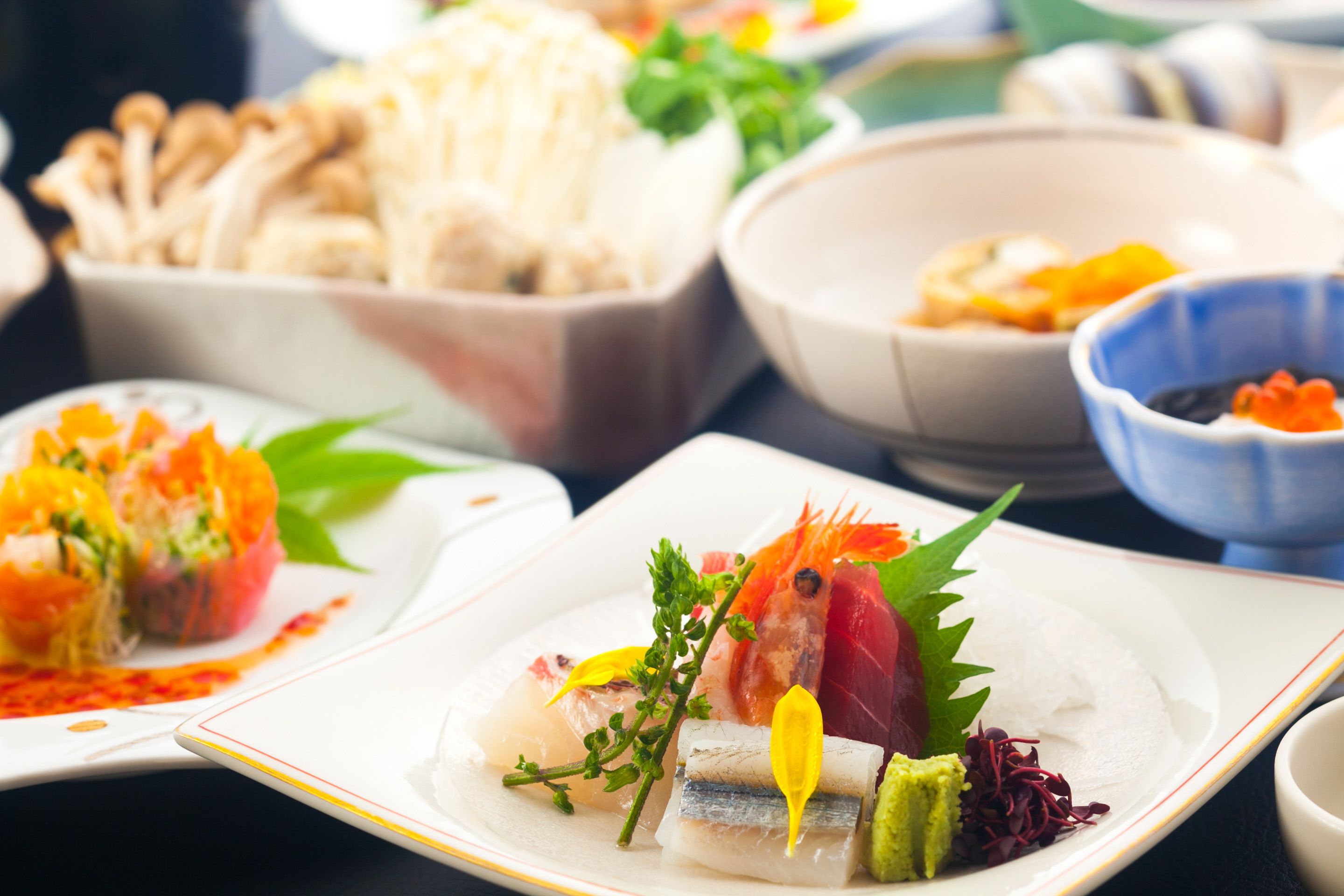 Variedad de platillos sobre una mesa, incluyendo sushi y sashimi.