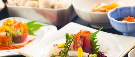 Variedad de platillos sobre una mesa, incluyendo sushi y sashimi.