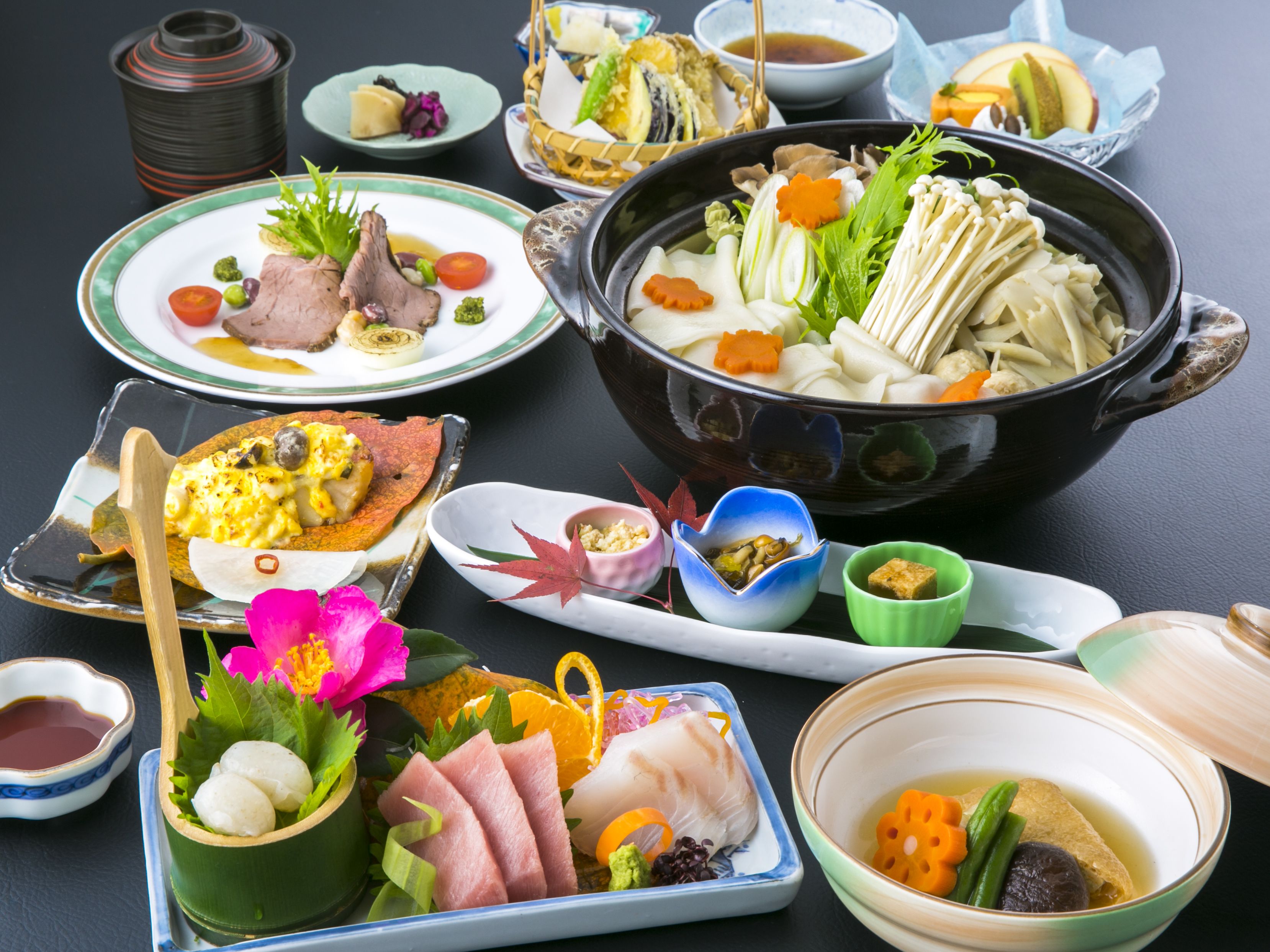A variety of dishes including a large pot of soup, plates with meat and vegetables, and small bowls with condiments.