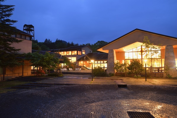 Stroll through the serene courtyard, surrounded by lush greenery and a prominent stone pillar.