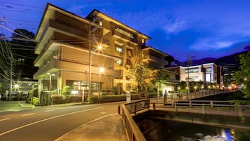 Un hotel de varios pisos con un diseño arquitectónico moderno, con balcones y un puente sobre una masa de agua.