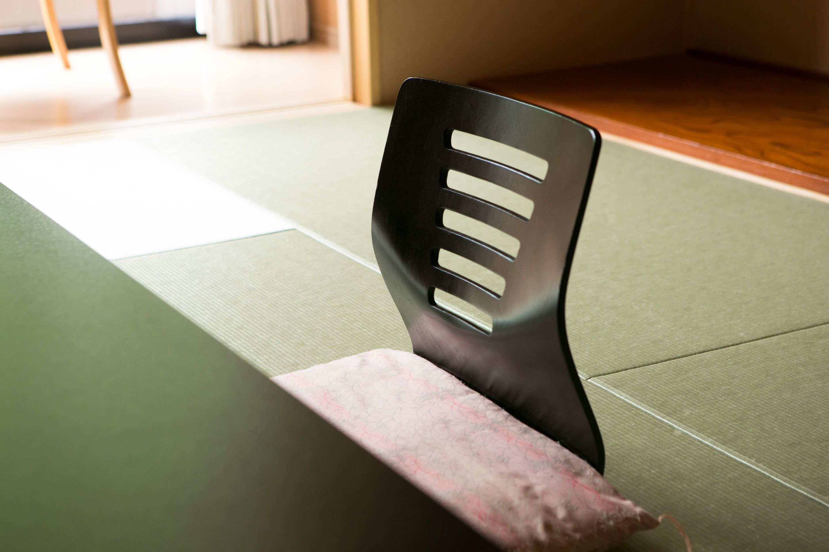 A chair with a black backrest and a wooden seat on a green mat.