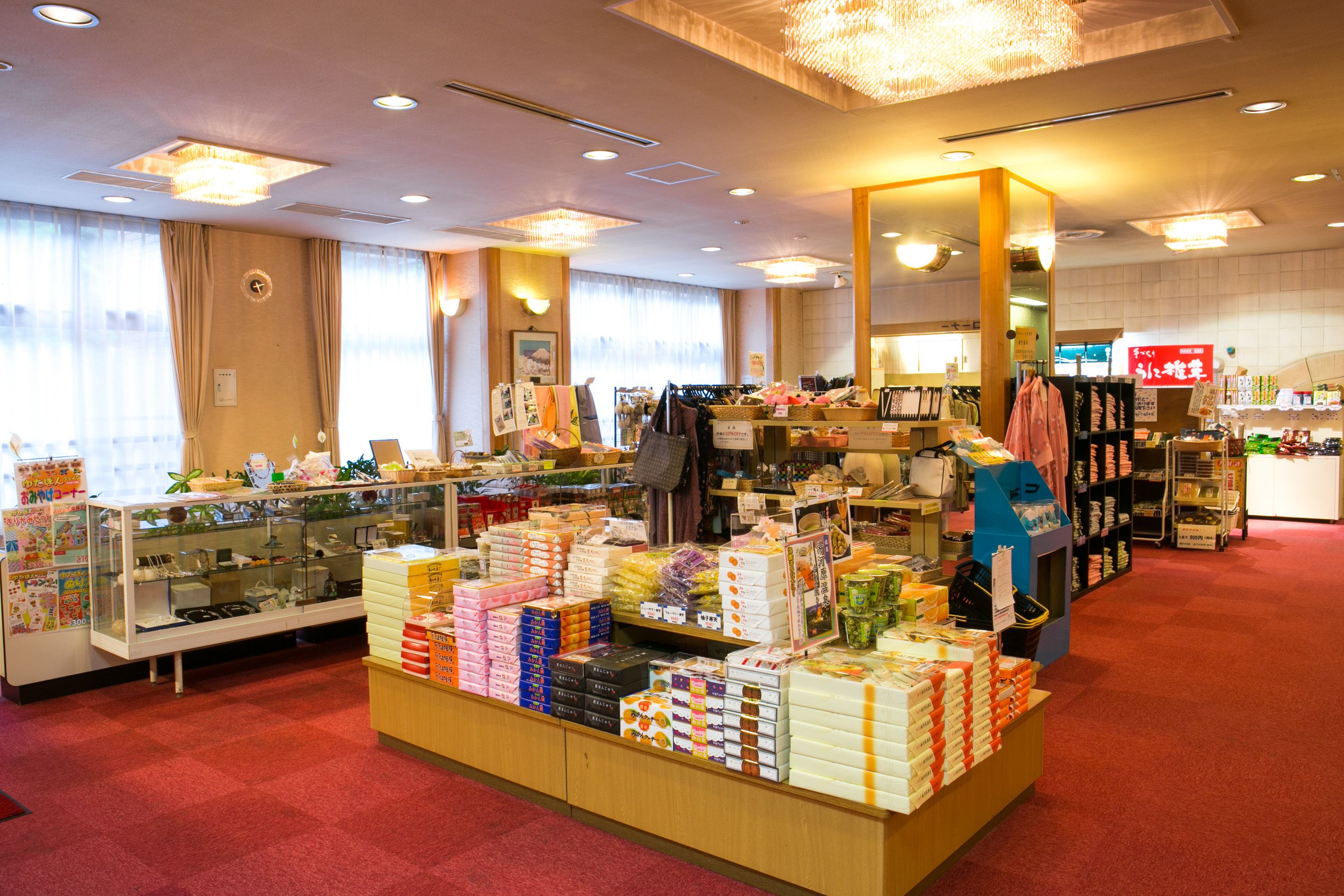 A hotel lobby with a display of various products, a reception desk, and a large mirror.