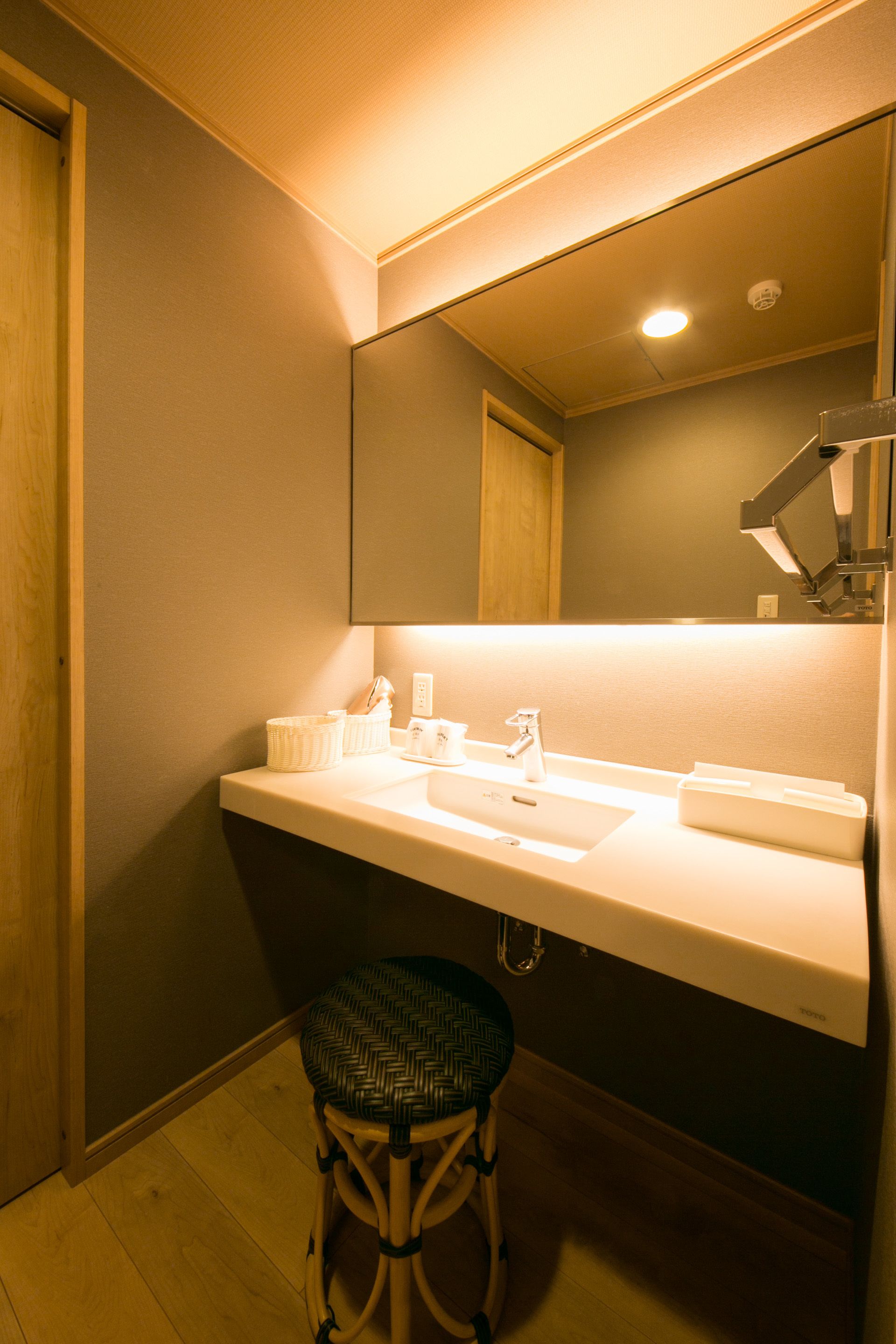 A bathroom with a white sink, mirror, and a stool.