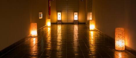 A corridor with tiled flooring and wall-mounted lights.