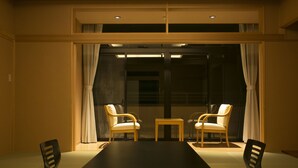 A room with a dark wooden table, two chairs, and a small wooden side table. - Yugawara Mizunokaori (Yugawara)