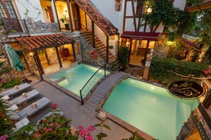 A rooftop swimming pool with a stone wall, a wooden deck, and lounge chairs. - Le Charcoa Hotel (Chiang Mai)