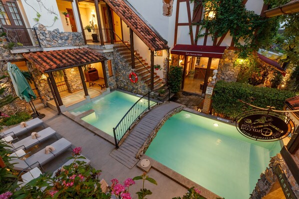 Una piscina al aire libre, sombrillas, sillones reclinables de piscina