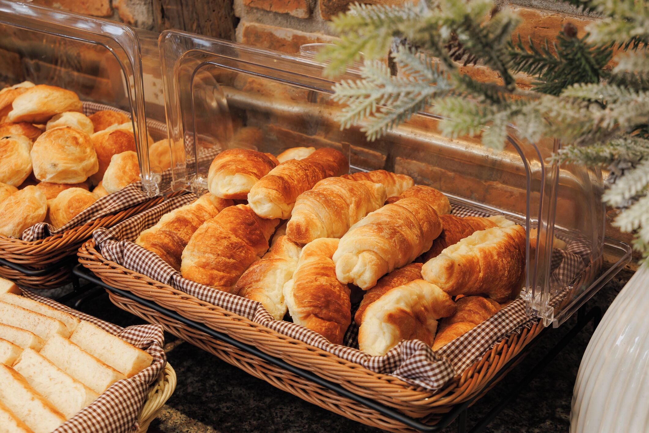 Une variété de produits de boulangerie, notamment du pain et des croissants, présentés dans des paniers et une vitrine.