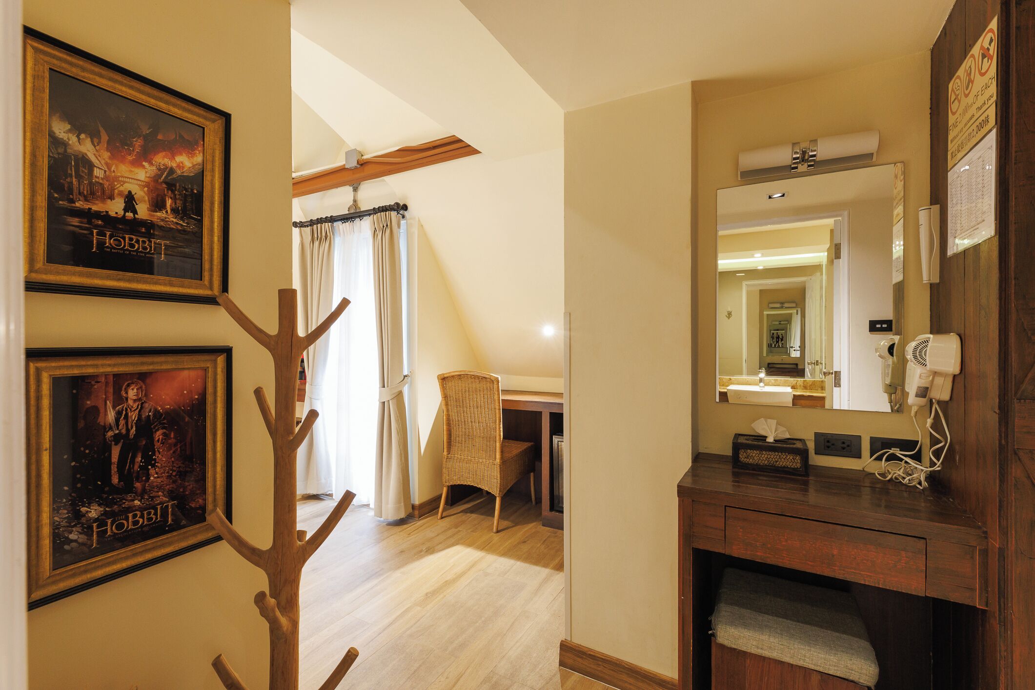 Habitación de hotel con piso de madera, un espejo grande, tocador de madera y carteles enmarcados en la pared.