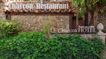 The exterior of Charcoa Restaurant with a stone facade and a sign indicating it is part of LE Charcoa HOTEL.