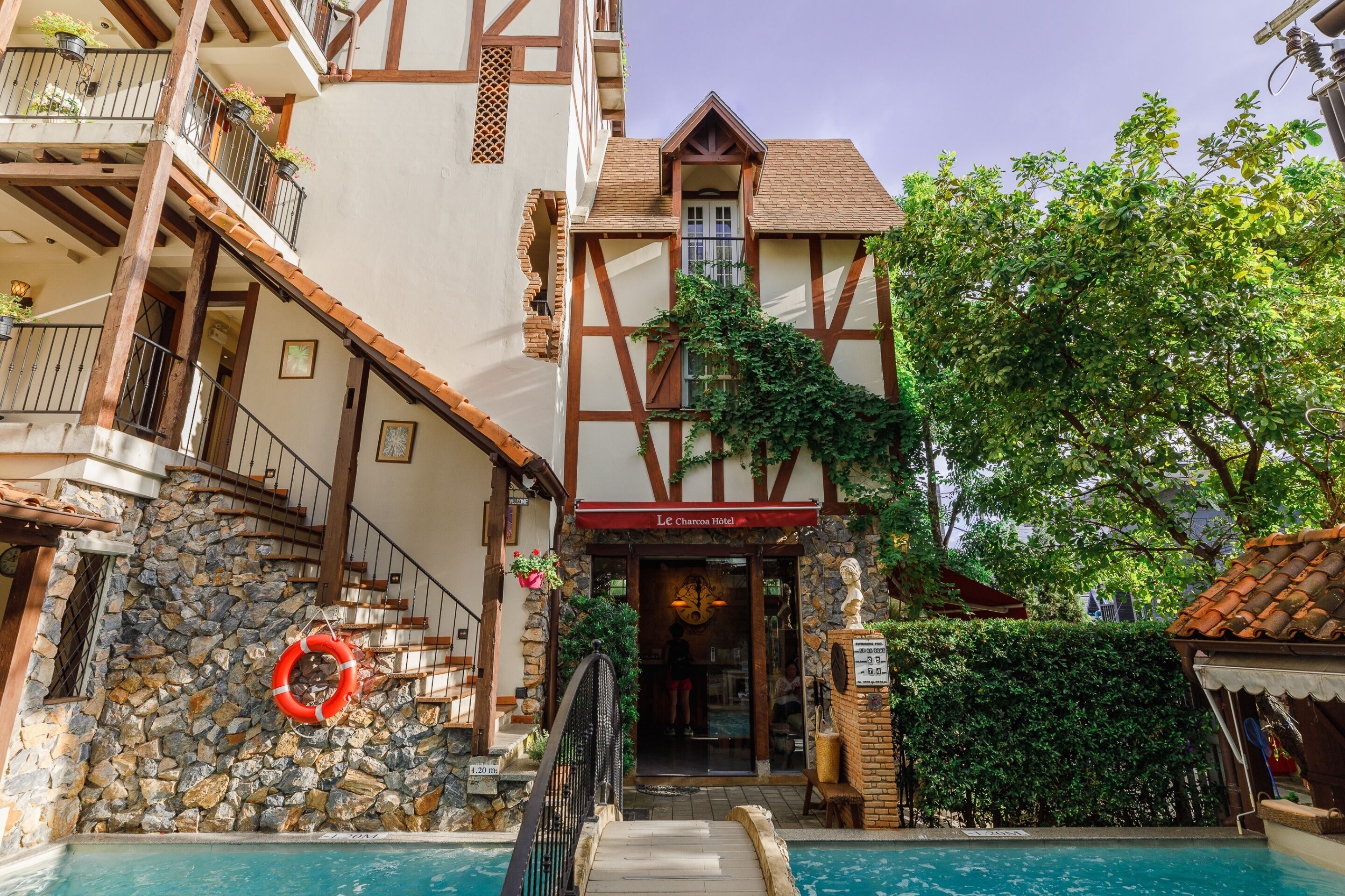 A traditional European-style hotel with a stone facade, wooden balconies, and a pool area.