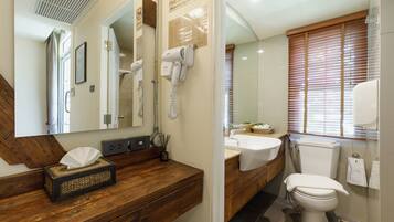 A bathroom with a wooden vanity, a mirror, a hairdryer, a sink, and a toilet.