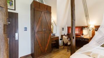 Un dormitorio con un armario de madera, un escritorio con silla, una cama con dosel y un pequeño calentador.