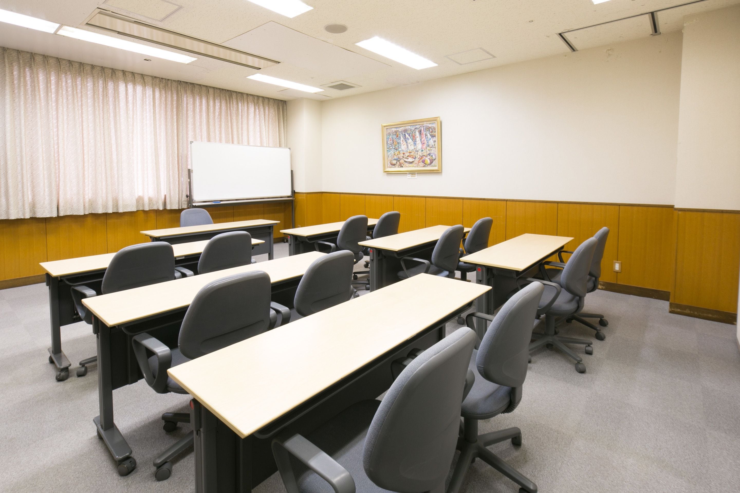 A conference room with multiple tables and chairs, a whiteboard, and a framed picture on the wall.