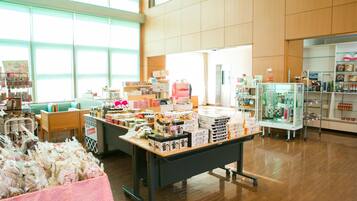 A spacious indoor area with a wooden floor, a central display table with various items, and a seating area with green chairs.