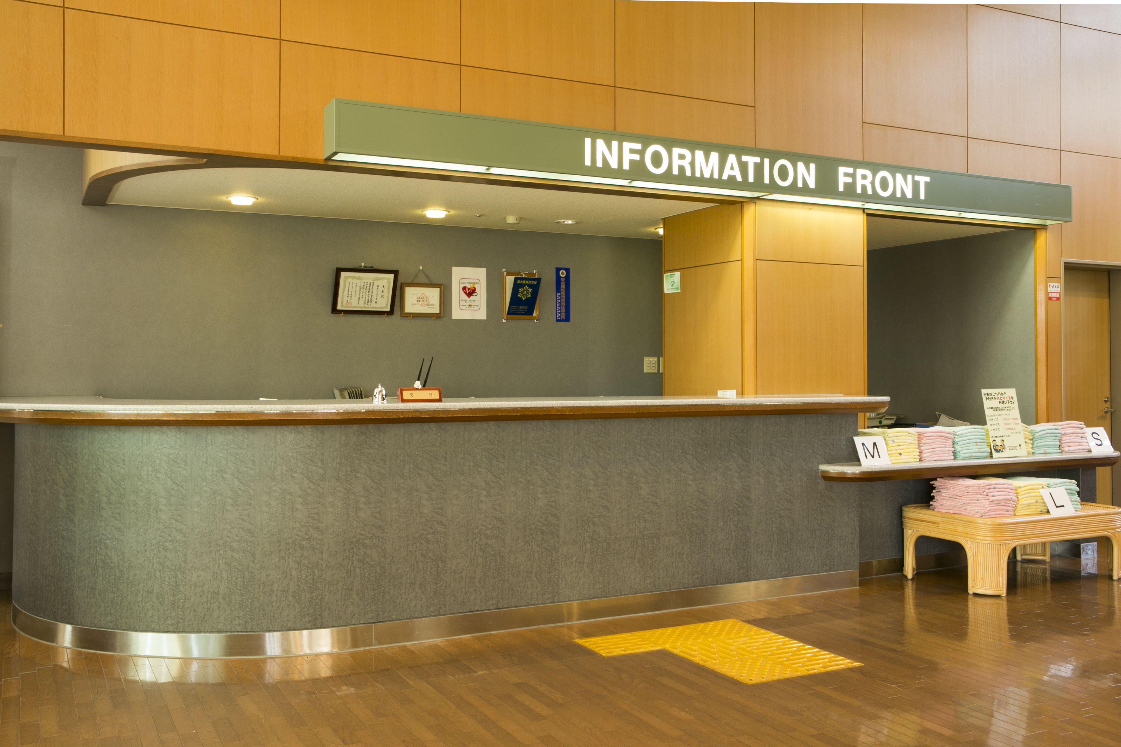 Un mostrador de recepción con un cartel que dice "INFORMATION FRONT" y una pequeña mesa de exhibición con folletos y cartas.