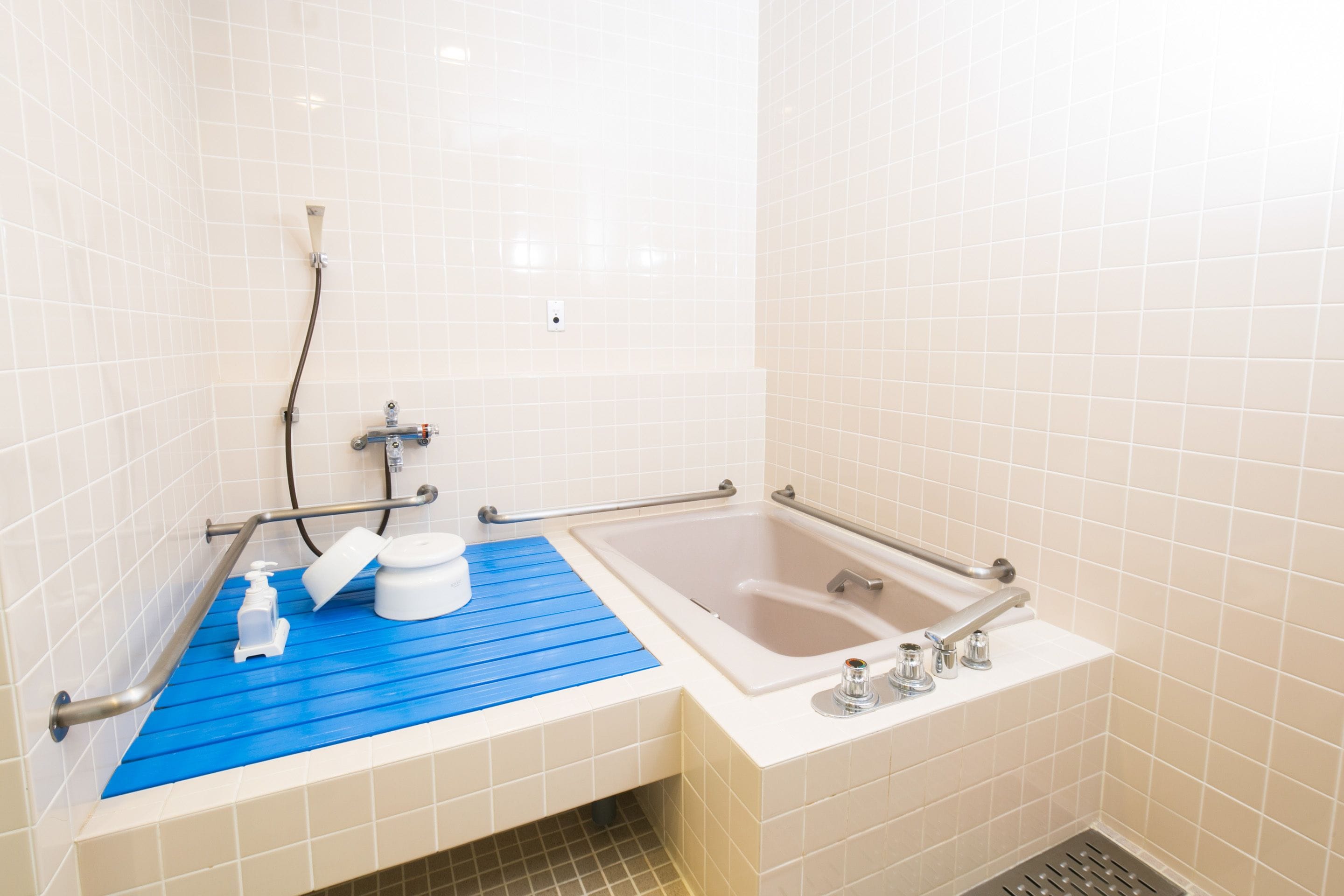 Un baño con una bañera blanca, un tapete de ducha azul y un inodoro blanco.