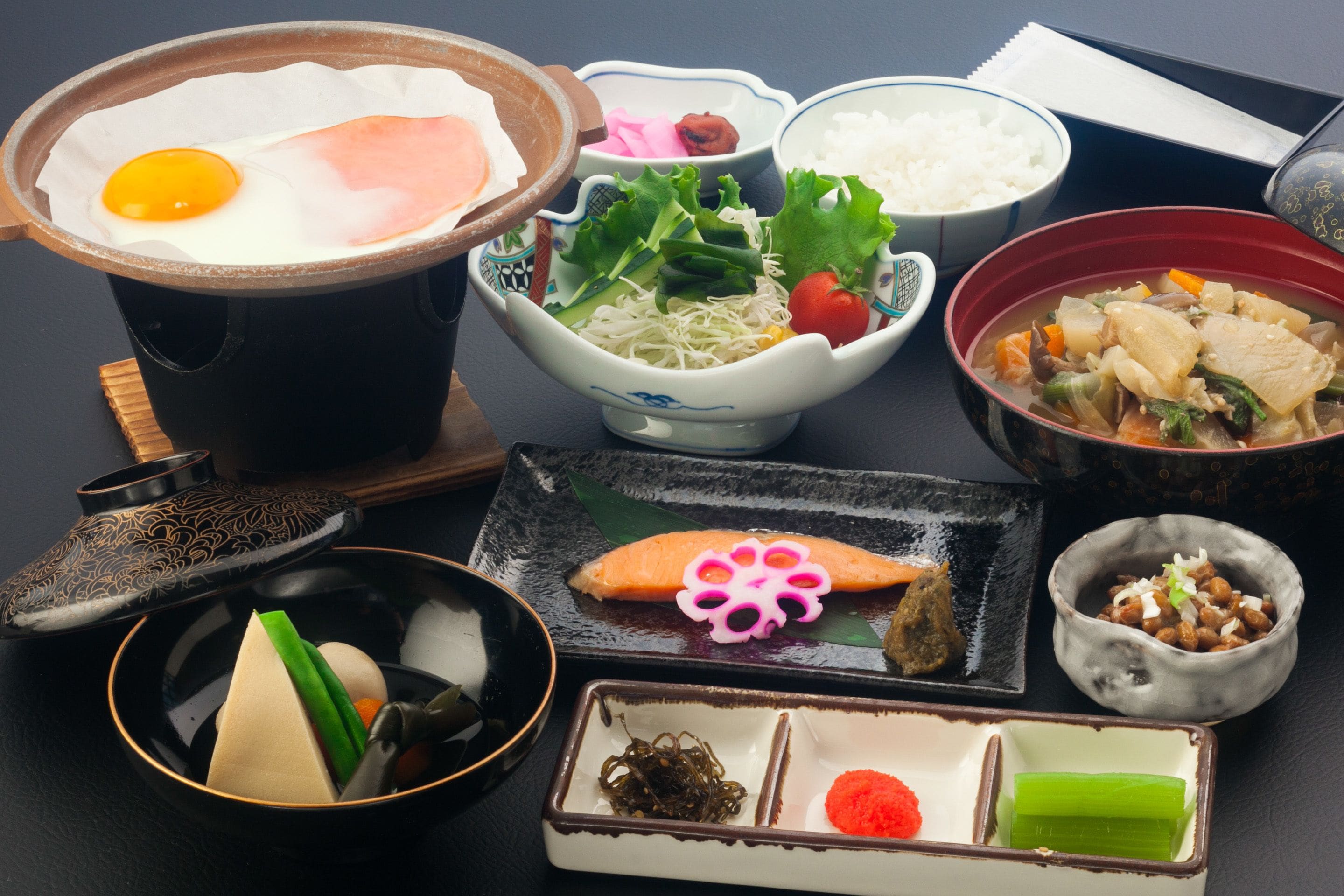 Un assortiment de plats japonais, comprenant un bol de riz, une assiette de sashimi et un bol de soupe.