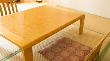 Ein traditioneller japanischer Raum mit Tatami-Matten, einem Holztisch und Stühlen.