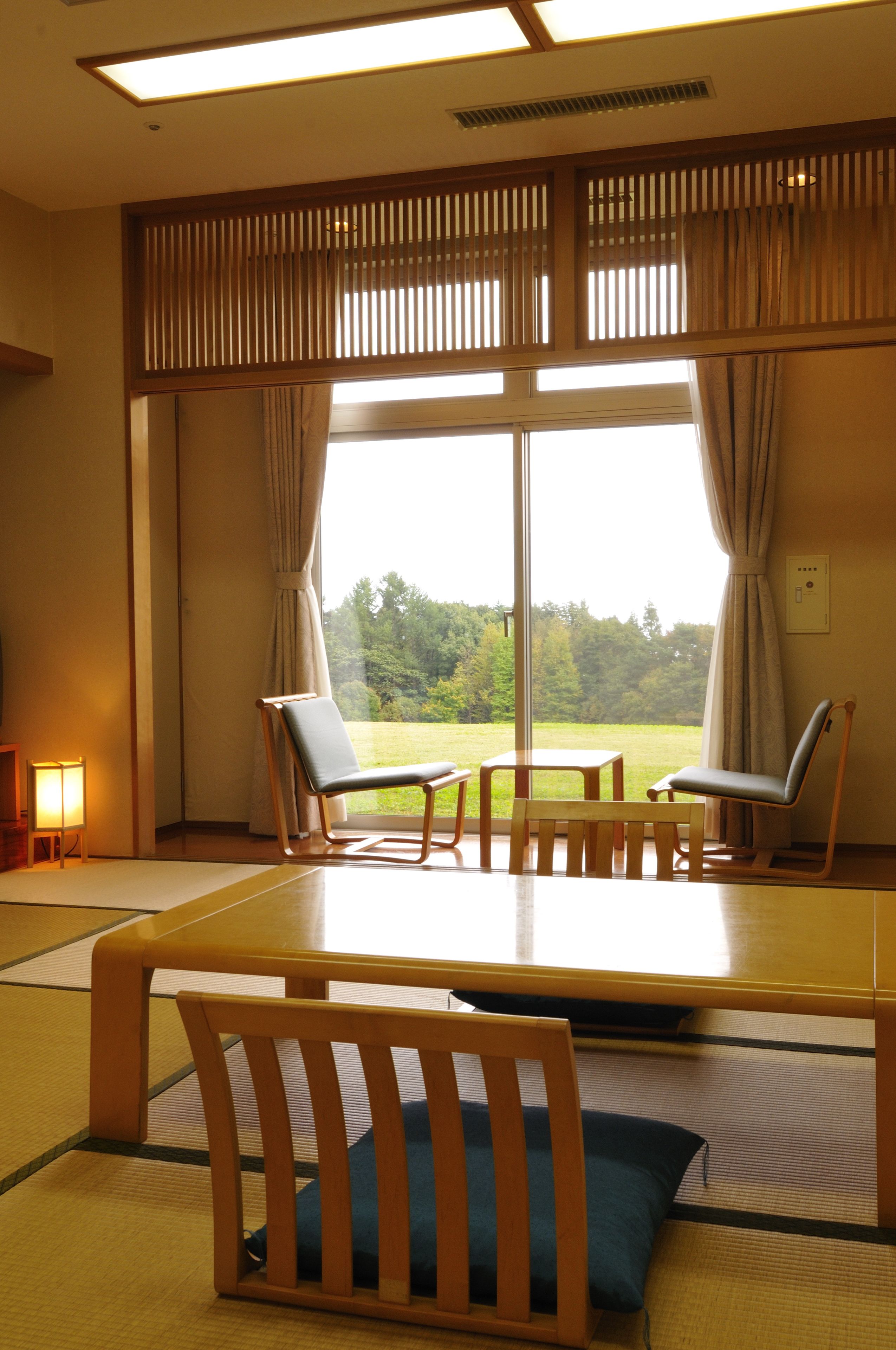 A traditional Japanese room with tatami flooring, a low table, and two chairs.