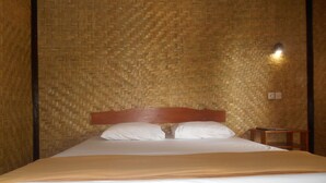 Una cama con cabecera de madera, ropa de cama blanca y un diseño trenzado en la pared.