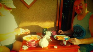 Una mesa de comedor con platos de comida, tazas, un hervidor y un tarro de mermelada.