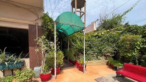 Uma área de recepção com placa, plantas em vasos, um banco vermelho e um reservatório de água.