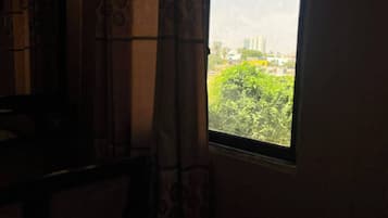 Een kamer met een raam dat uitkijkt over een groen gebied en gebouwen.