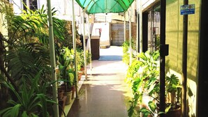 A covered walkway with potted plants on both sides, leading to a gated entrance. - Hilltop Hotel (Karachi)