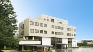 A modern building with a flat roof, multiple windows, and a covered entrance area. - Akoya Kaikan (Yamagata)
