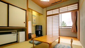 A traditional Japanese room with tatami flooring, a low wooden table, a television, and sliding shoji doors. - Akoya Kaikan (Yamagata)